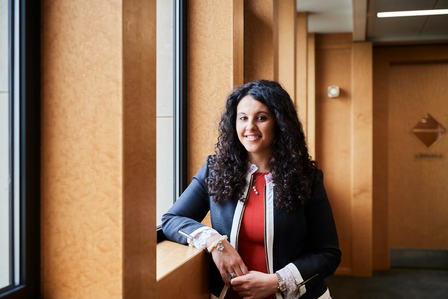 Woman smiling to camera leaning with one elbow on a window ledge in a corridor in an office environment