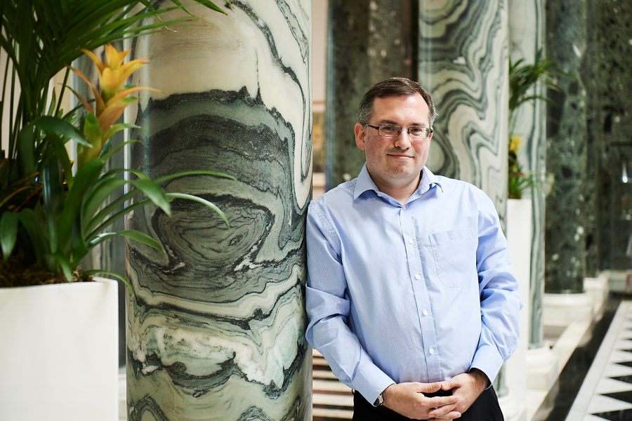 Man stood against a pilar smiling at the camera