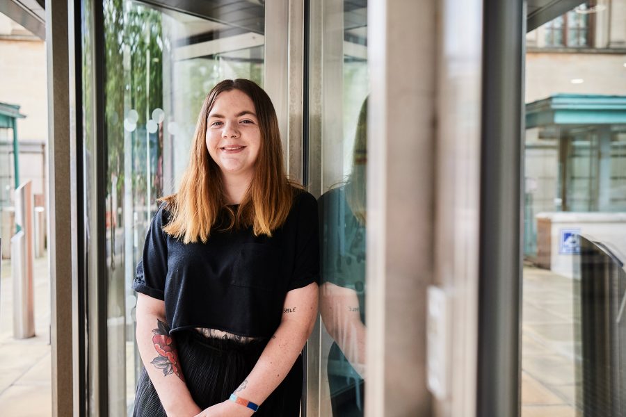 Woman stood by Aviva office doors smiling at camera