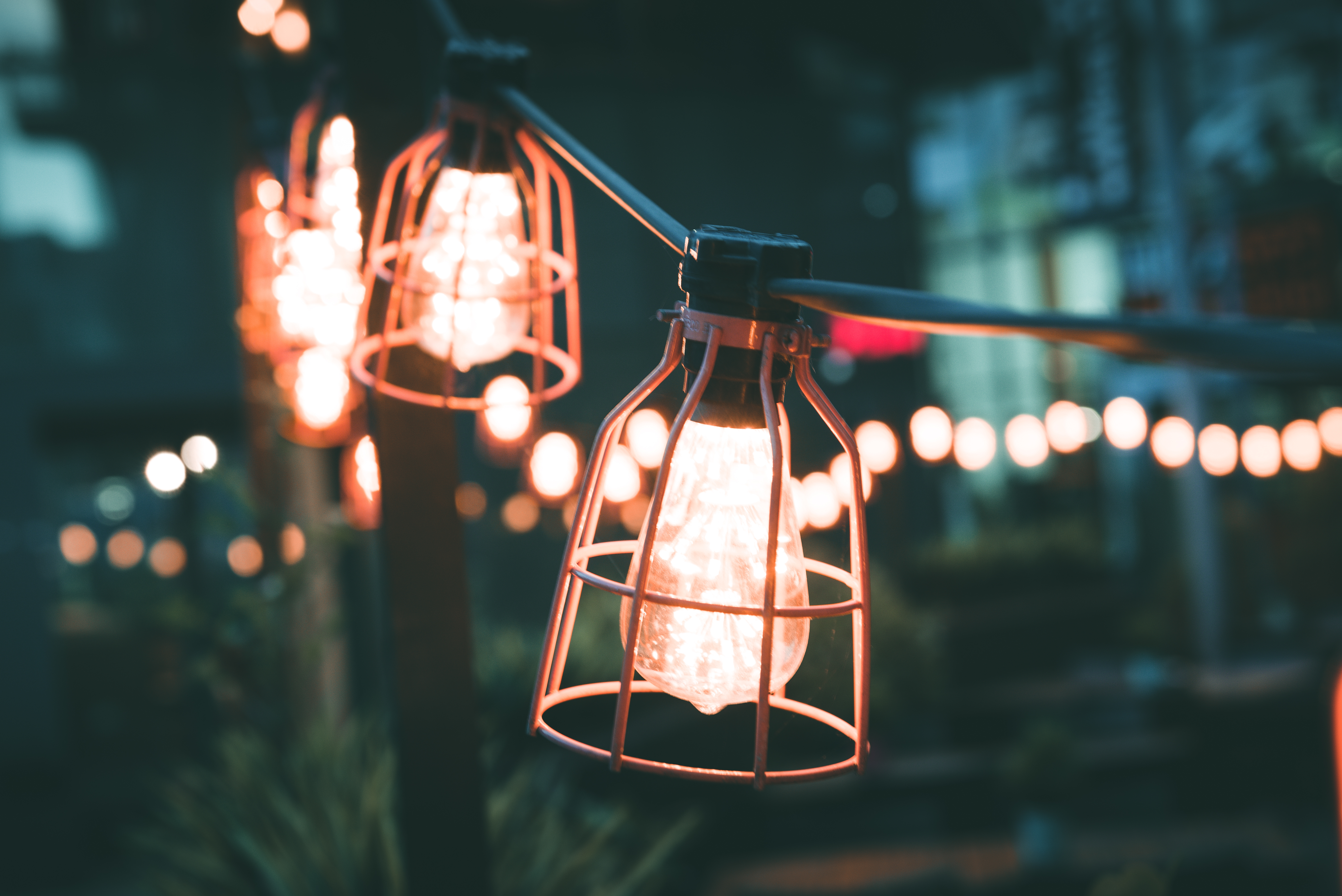 Close up shot of a couple of exposed bulbs encased in thick copper mesh strung up outside